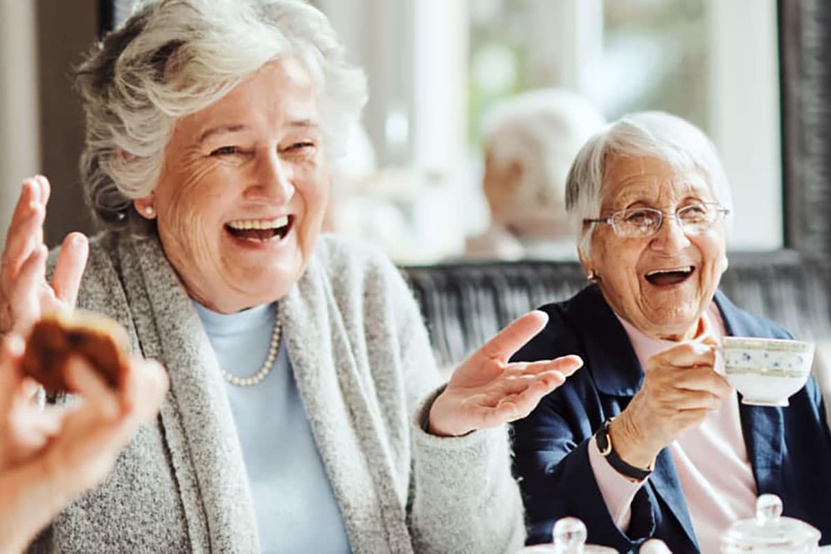 Two Women Laughing And Holding Their Hands Up